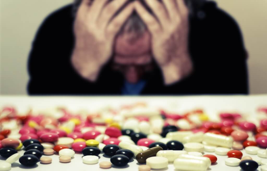 An image of a man with pills on the table