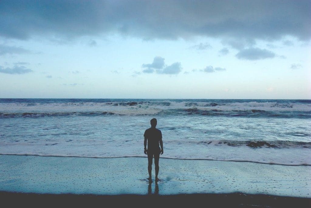 Man standing on a beach looking out at the ocean